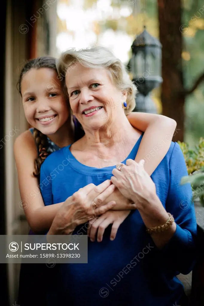 Grandmother and granddaughter hugging on porch