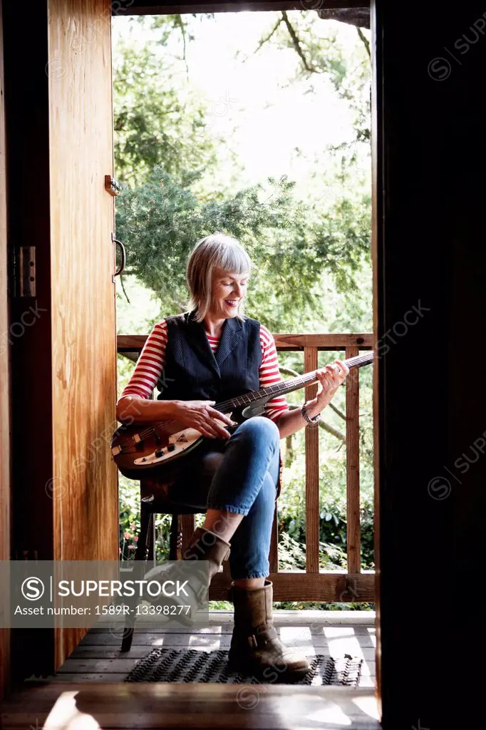 Caucasian woman playing guitar on porch