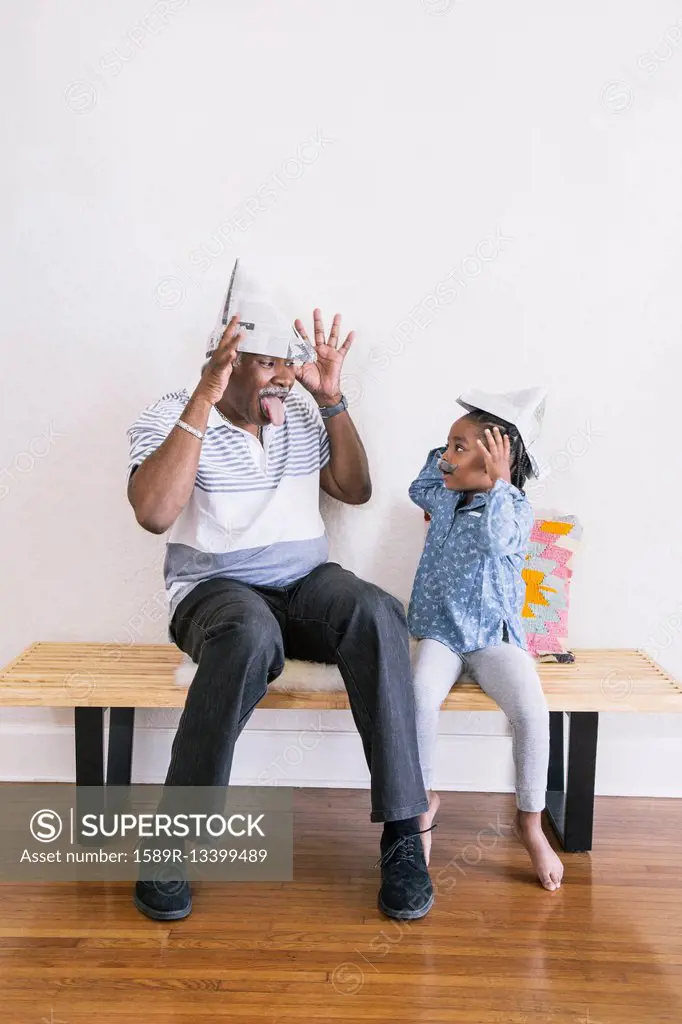 African American grandfather and granddaughter playing on bench