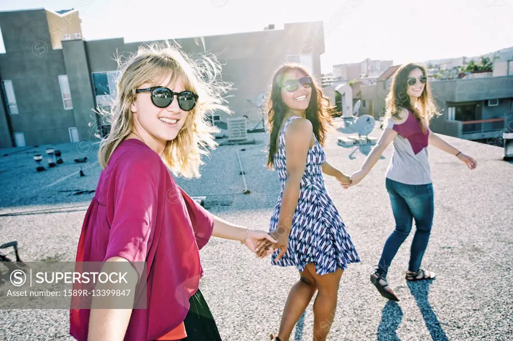 Women holding hands on urban rooftop