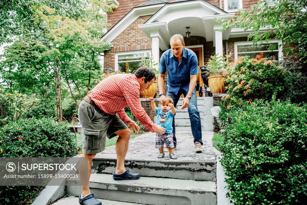 Gay fathers and baby son on steps