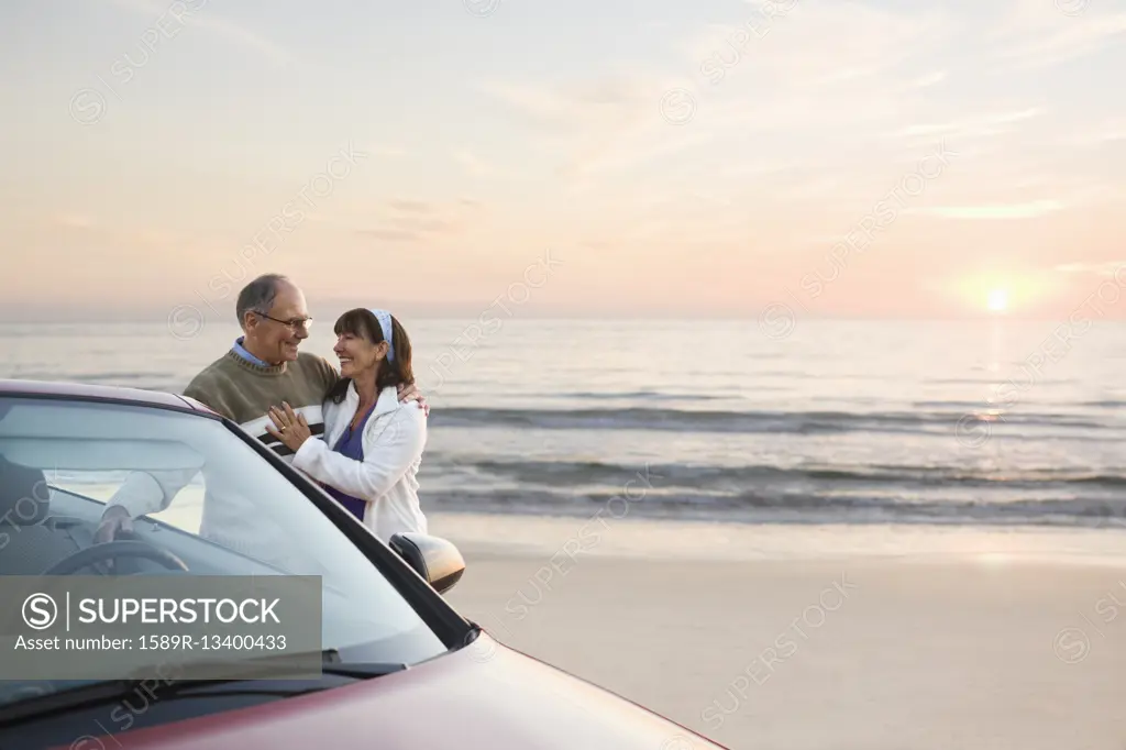 Older couple standing at car on beach