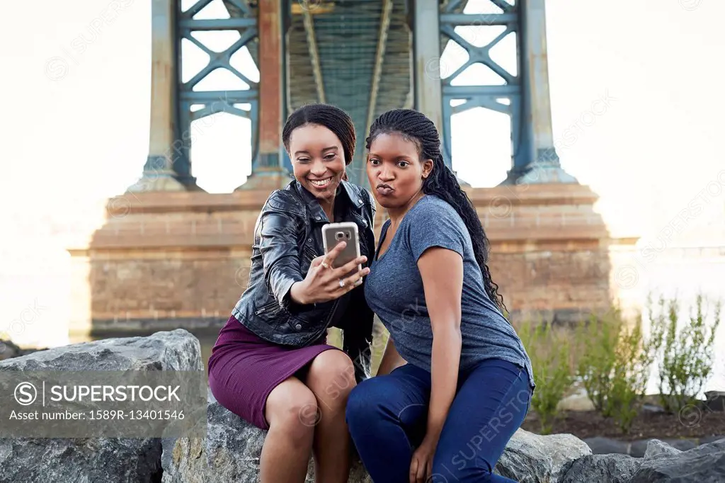 Black women posing for selfie at bridge