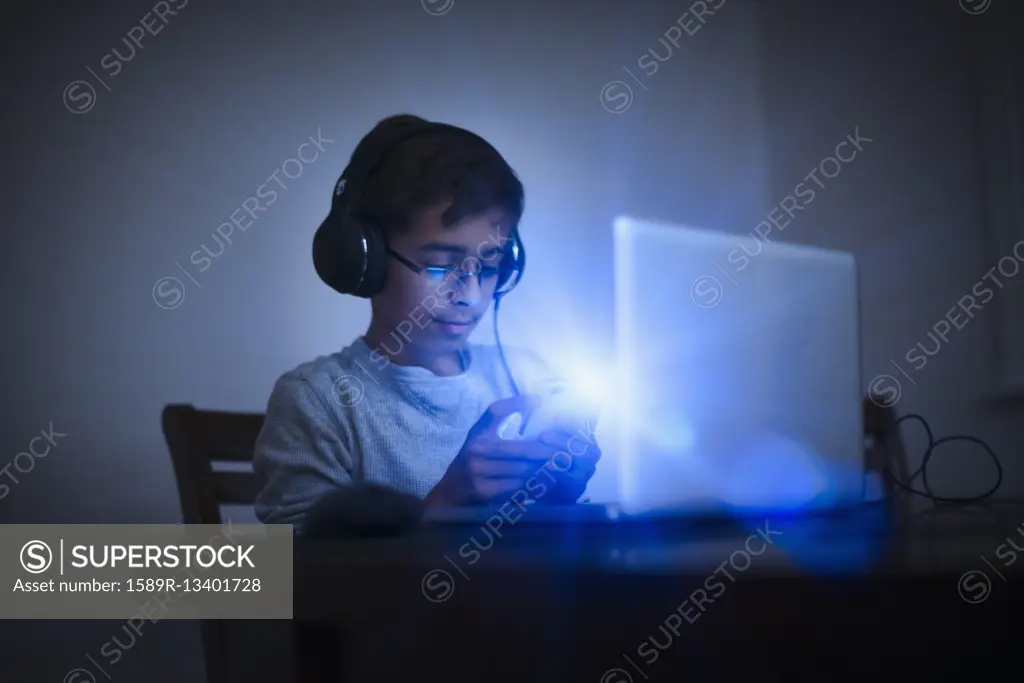 Mixed Race boy using cell phone and laptop