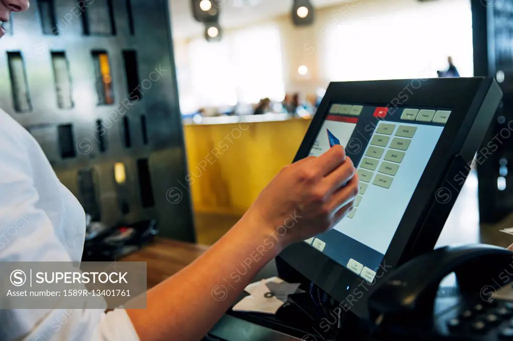 Caucasian cashier using touch screen to process credit card payment