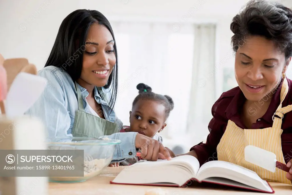 Black multi-generation family reading recipe in cookbook