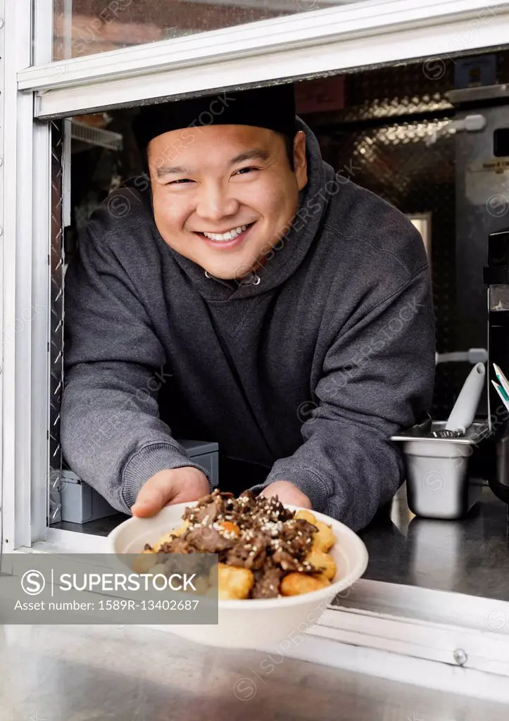 Proud Asian man showing bowl of food at food truck