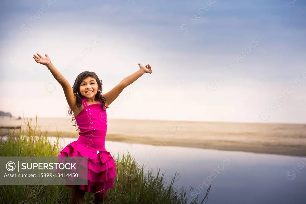 Hispanic girl cheering by still water