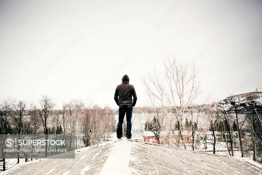 Caucasian man standing on snowy roof