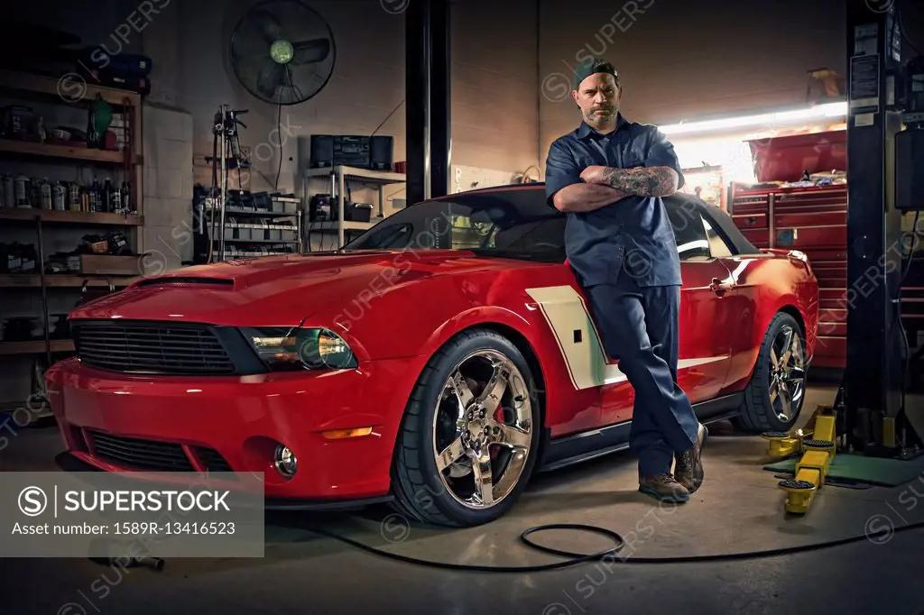 Caucasian mechanic posing on red sports car