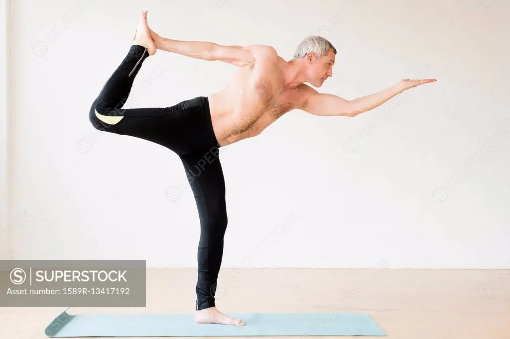 Older Caucasian man doing yoga on exercise mat