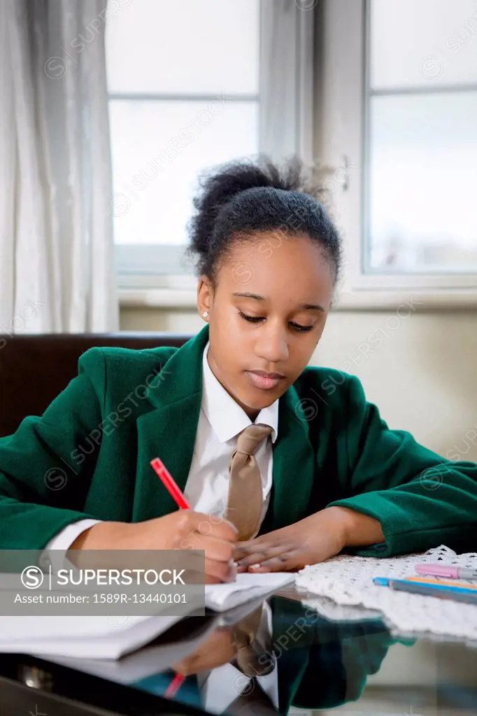 Black girl wearing school uniform doing homework