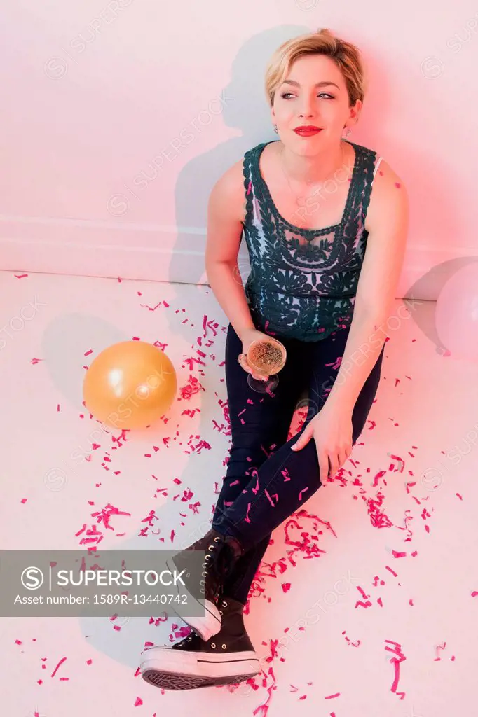 Caucasian woman sitting on floor at party covered in confetti