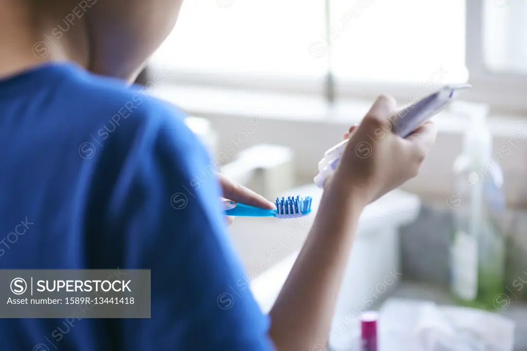 Hispanic by squeezing toothpaste onto toothbrush