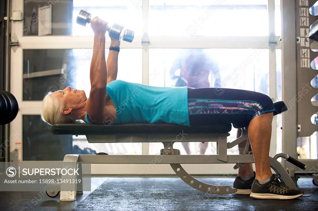 Older woman lifting dumbbells in gymnasium