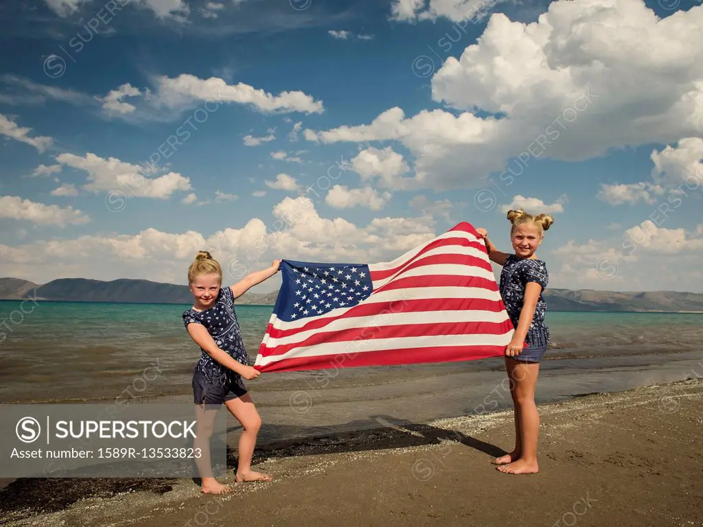 Caucasian girls holding American flag at beach