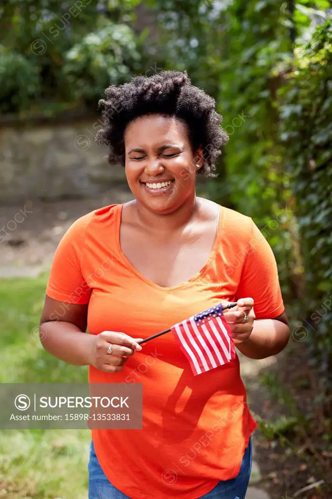 Portrait of laughing Black woman holding little American flag