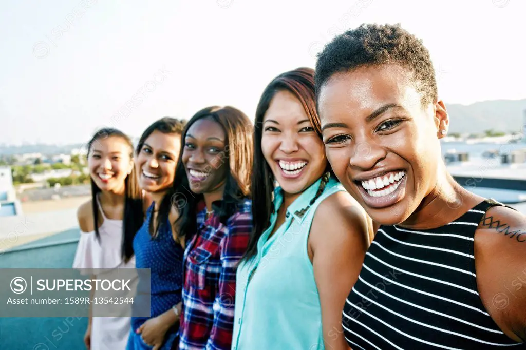 Smiling women standing in a row on rooftop