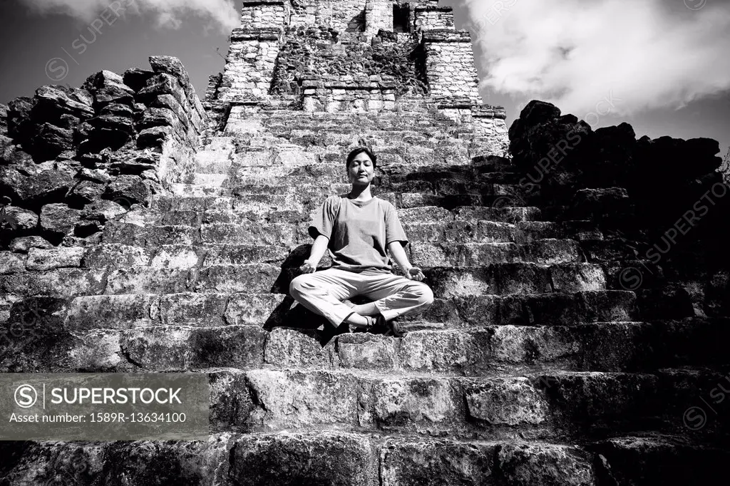 Japanese woman meditating on staircase to temple