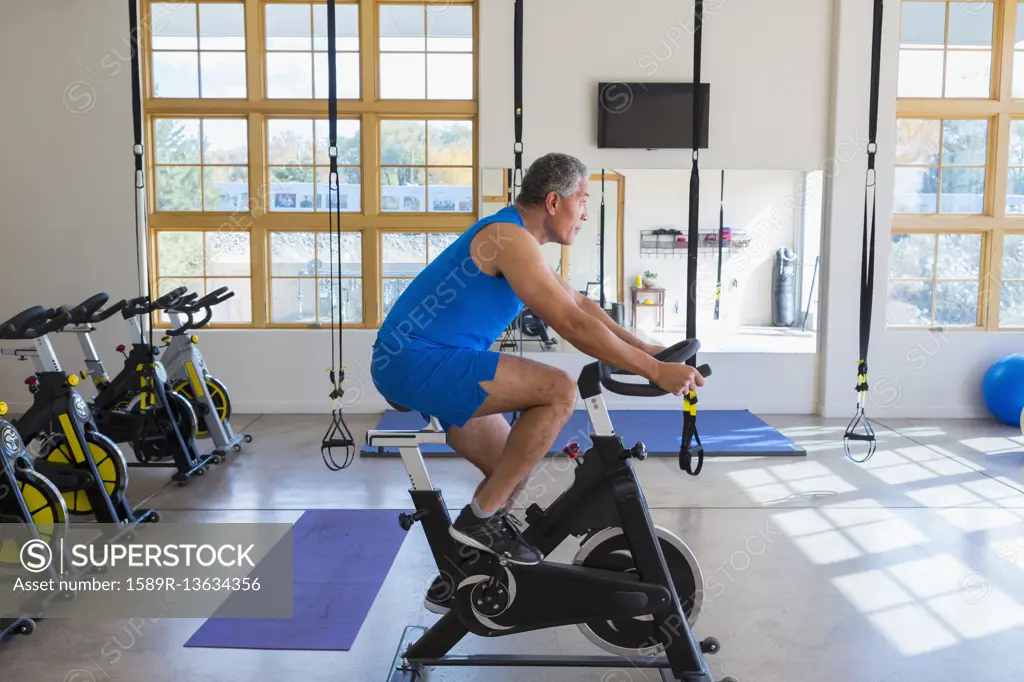 Mixed Race man riding stationary bicycle in gymnasium