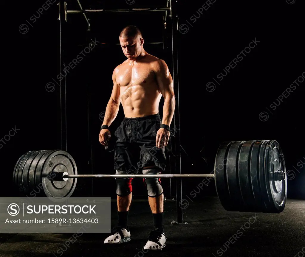 Man dropping heavy barbell in gymnasium SuperStock