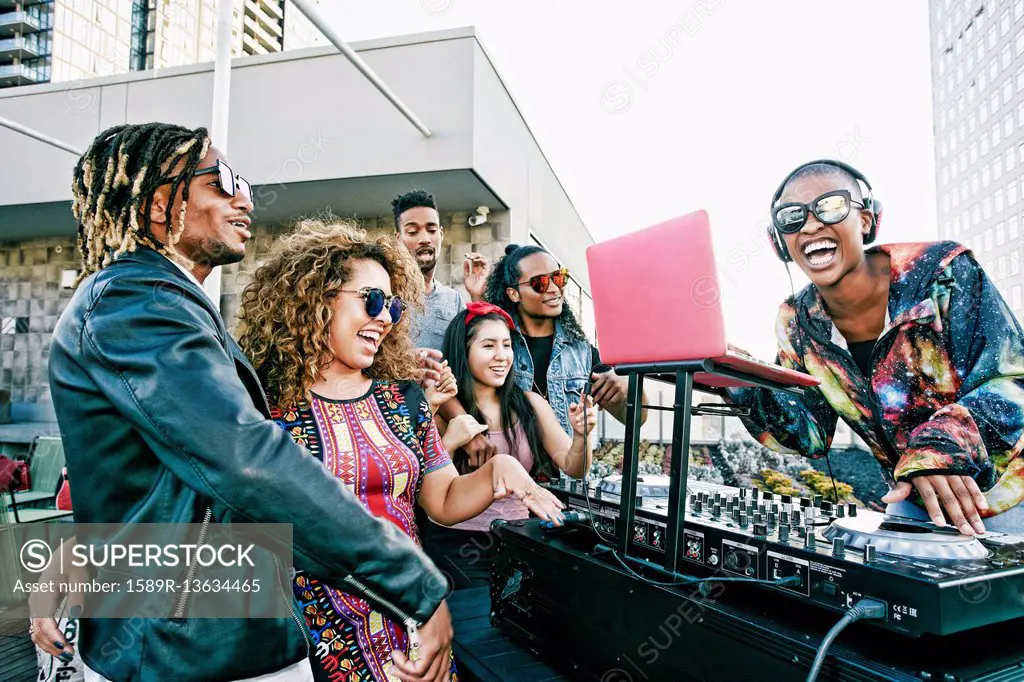 Friends smiling with DJ on urban rooftop