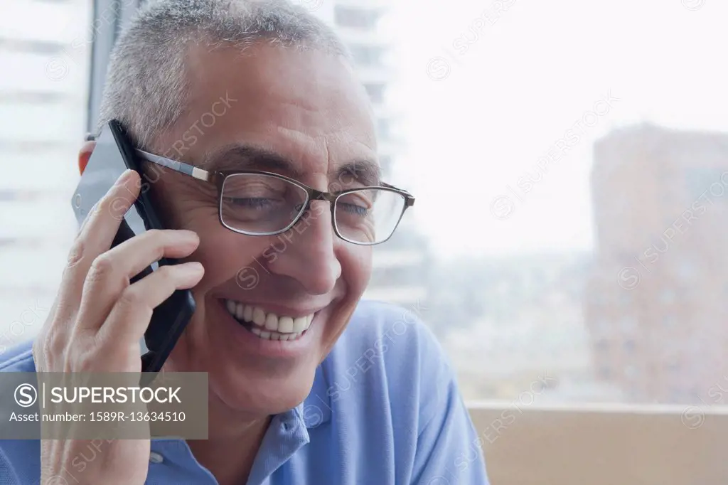 Smiling Hispanic man talking on cell phone