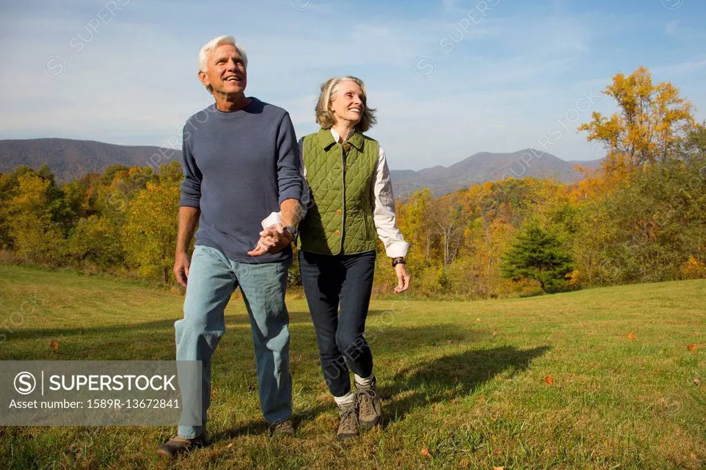 Older Caucasian couple walking in field