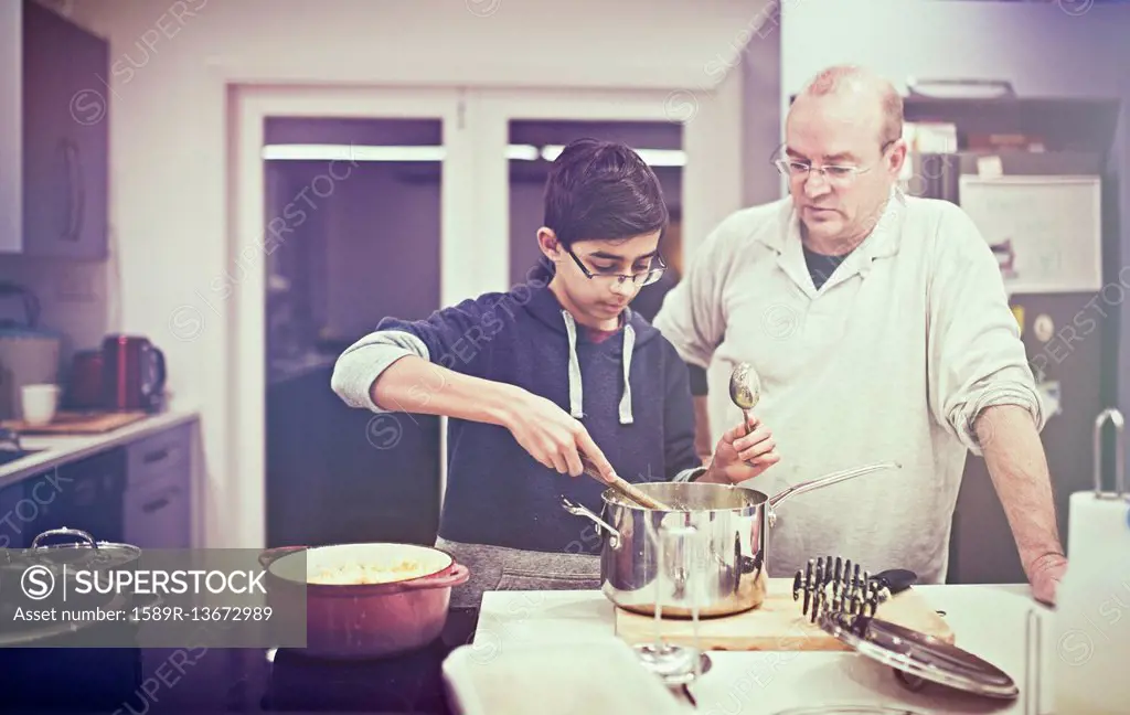 Father watching son cooking in kitchen