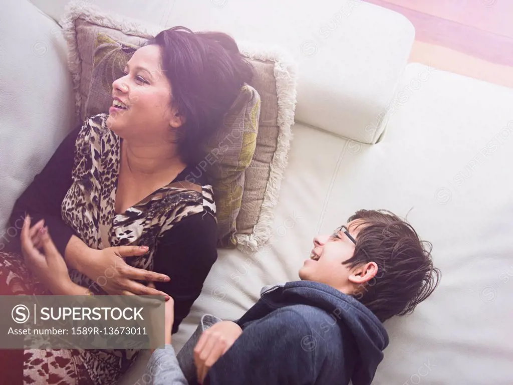 Mother and son laying on sofa and laughing