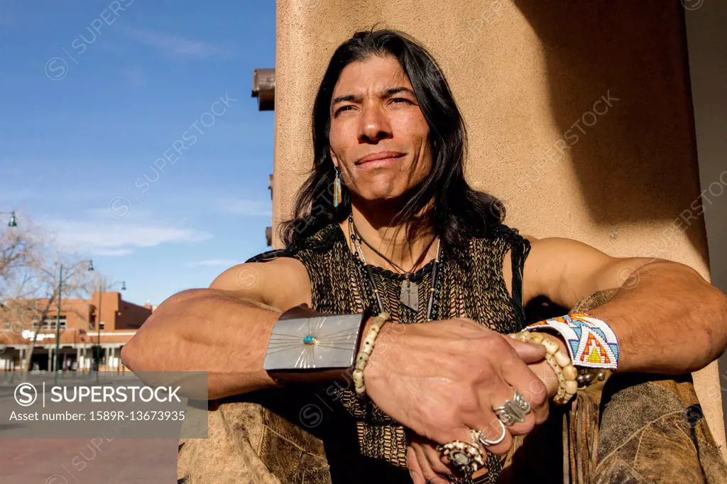 Native American man sitting against post