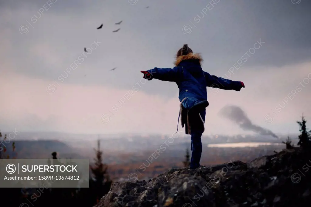 Caucasian girl balancing on rocks imitating flying birds