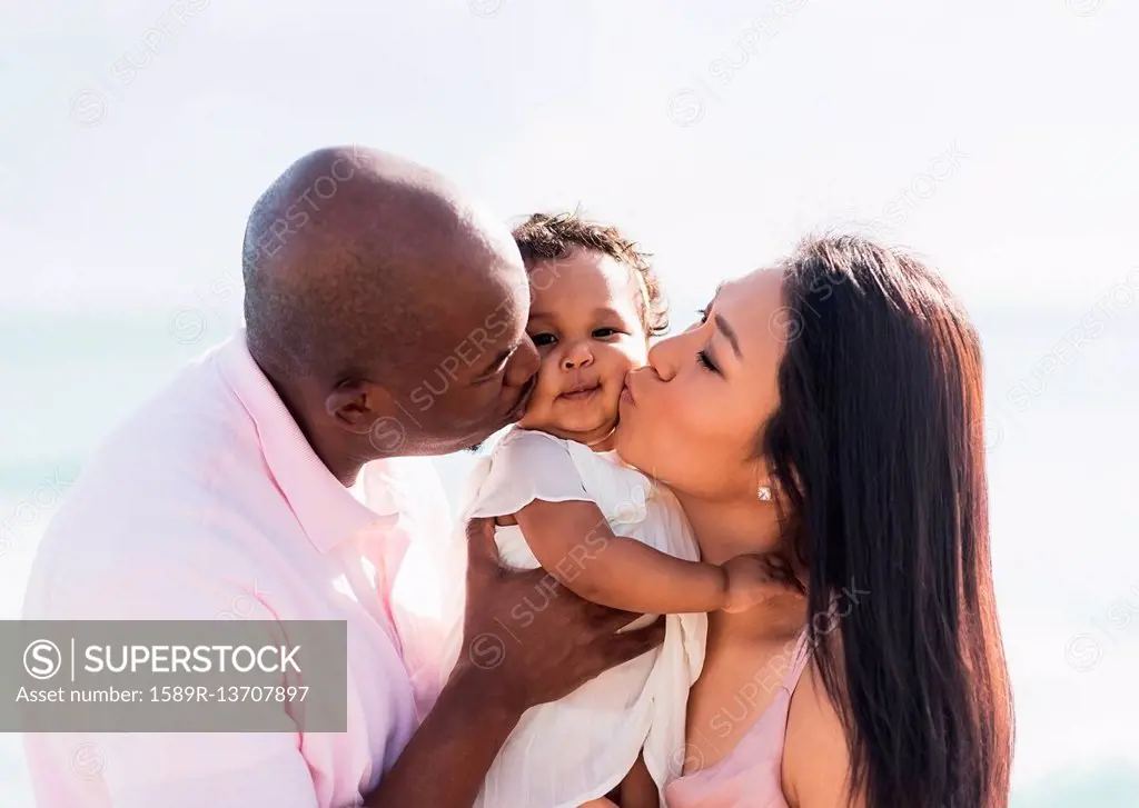 Couple kissing cheeks of baby daughter