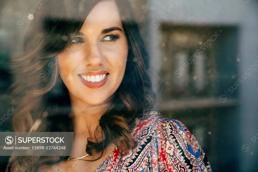 Portrait of smiling Mixed Race woman behind window