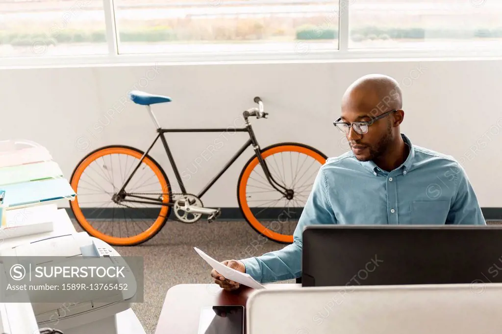 African American man reading paperwork in office