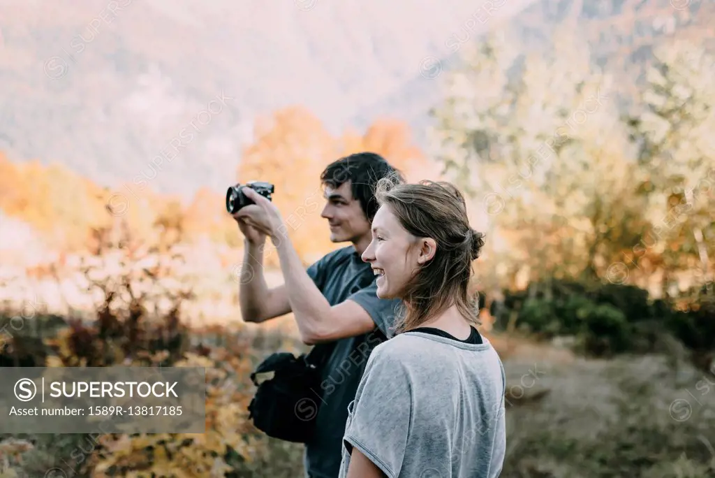 Caucasian couple photographing with camera in autumn