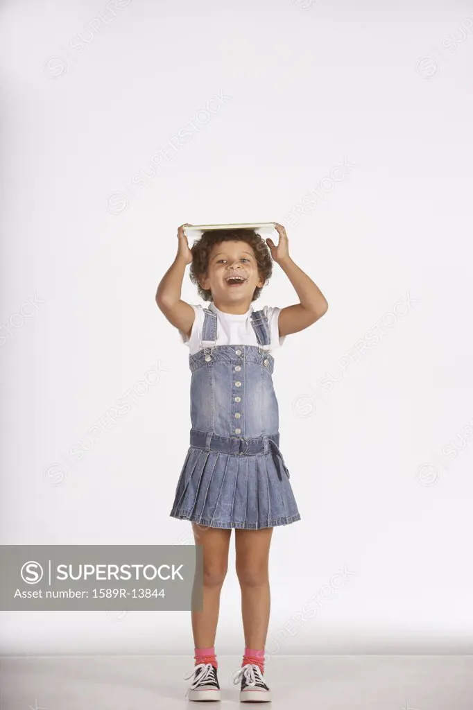 Portrait of girl balancing book on head