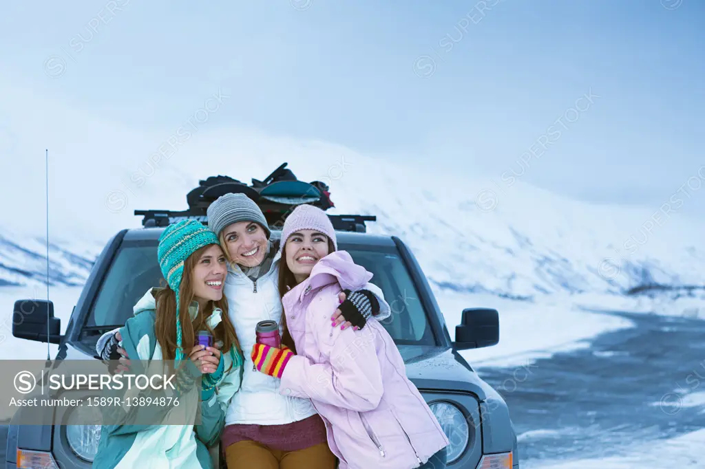 Women hugging near car in winter