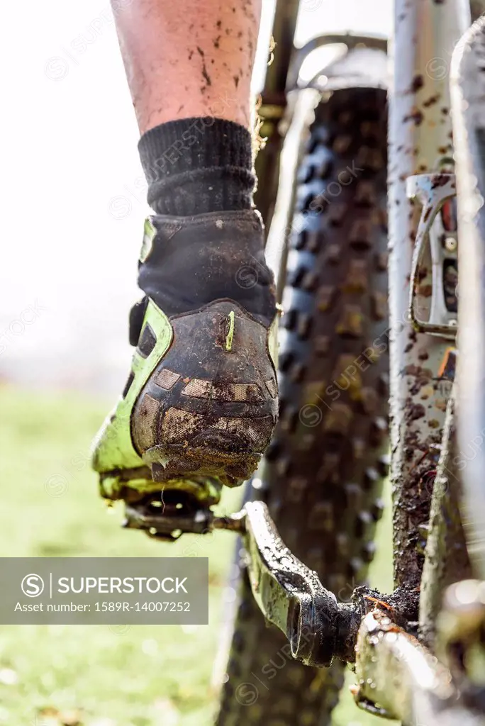 Leg of Caucasian man splattered in mud riding bicycle