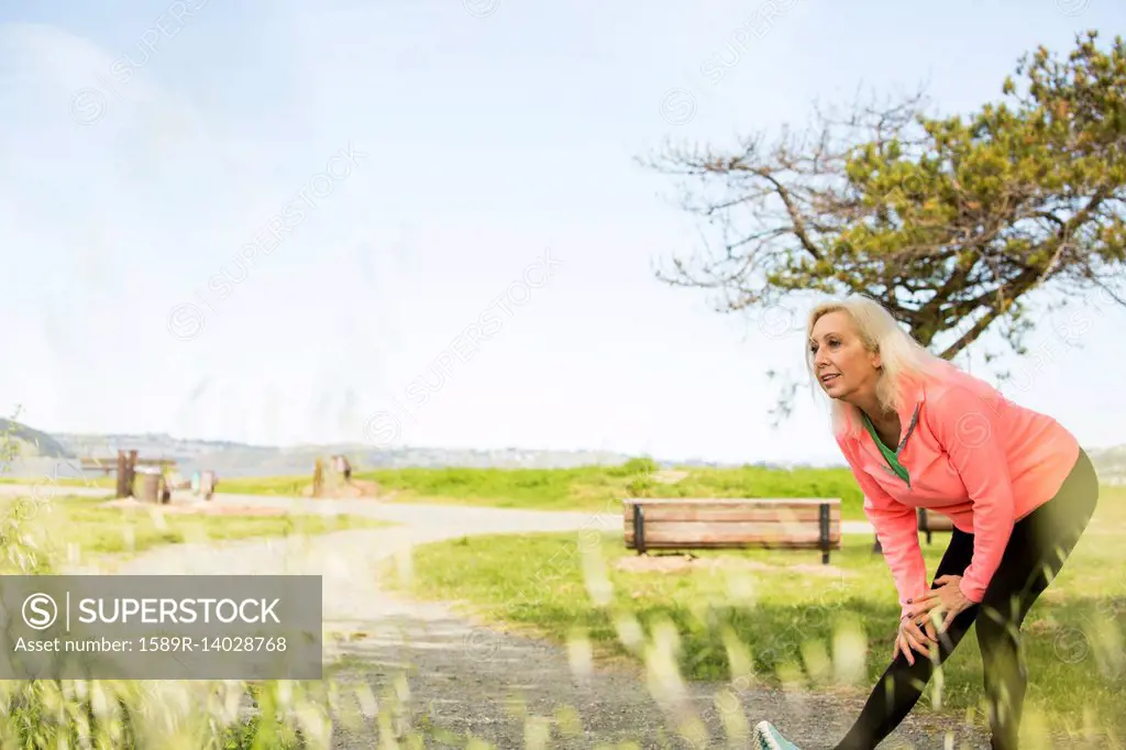 Older Caucasian woman stretching leg in park