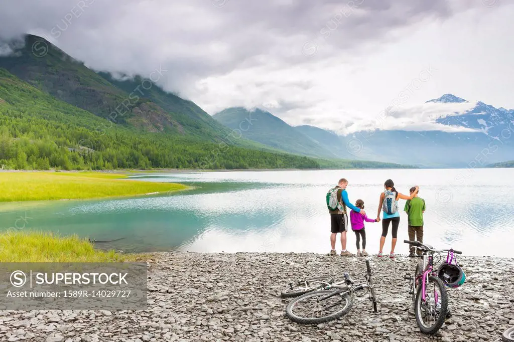 Couple with son and daughter riding bicycles near lake