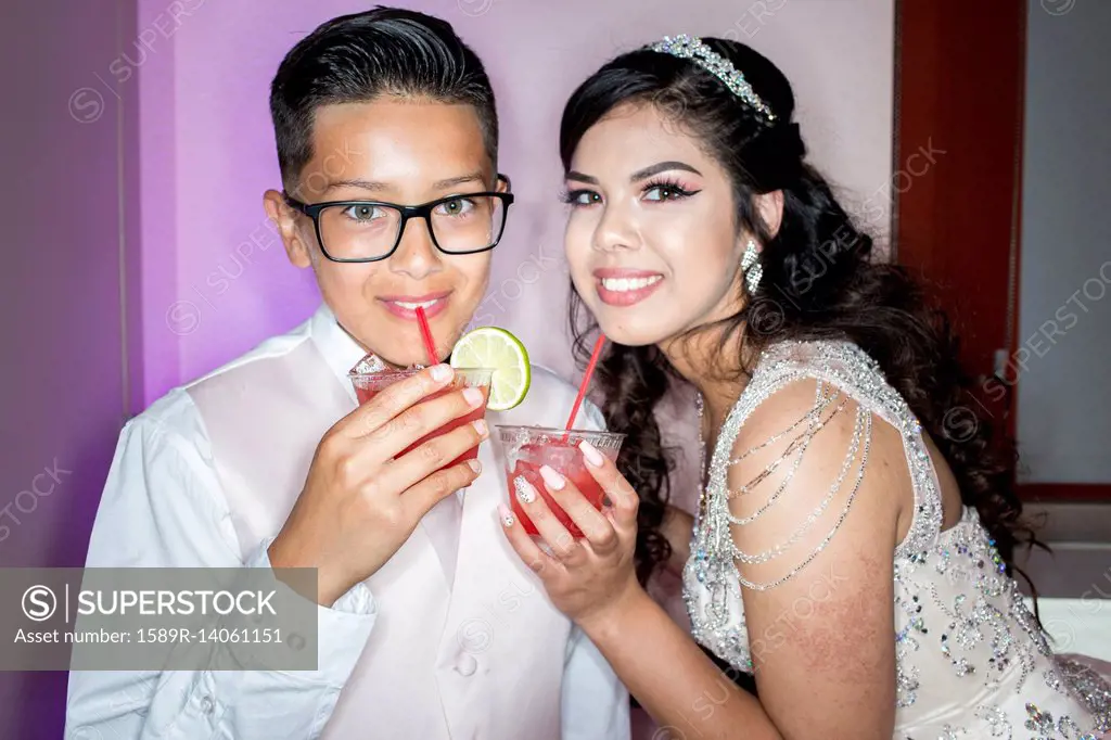 Hispanic boy and girl drinking beverages with straws