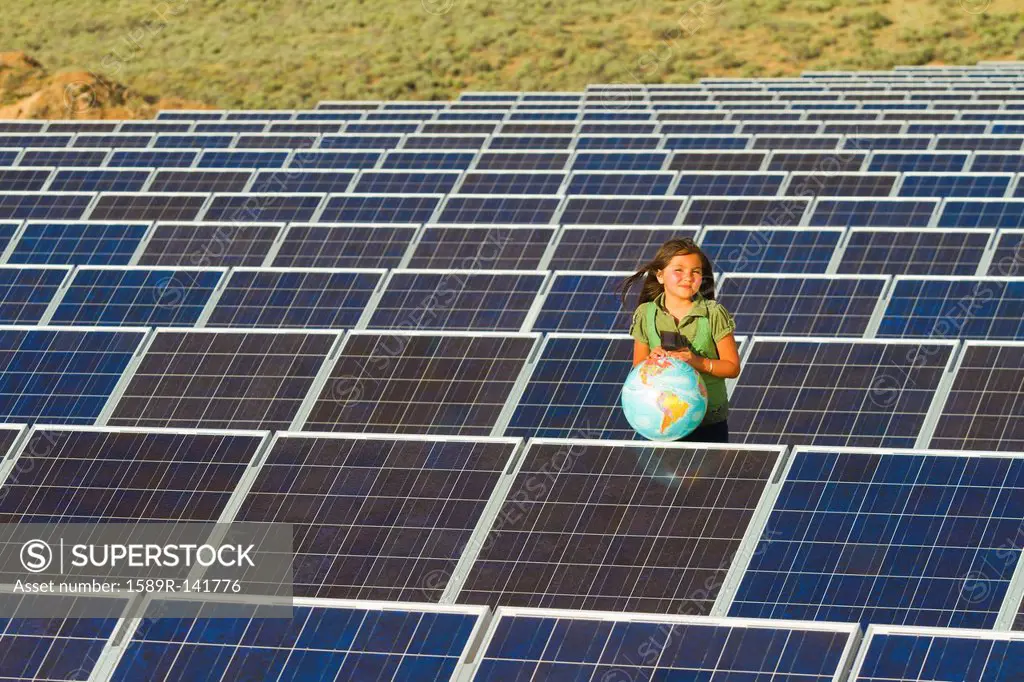 Native American girl standing near solar panels holding globe