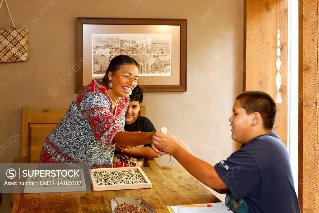 Mother and sons admiring baby turkey at table