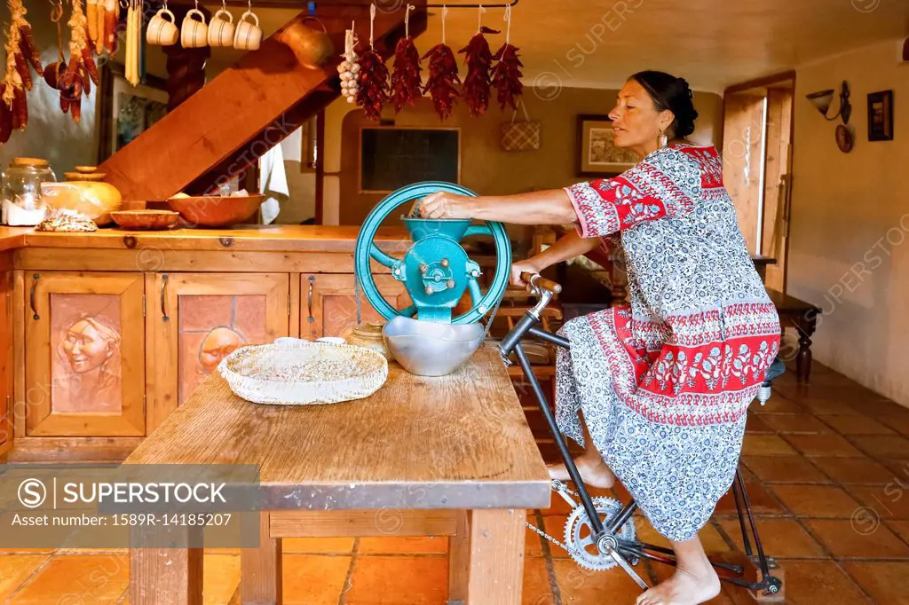 Woman pedaling to power grinder in kitchen