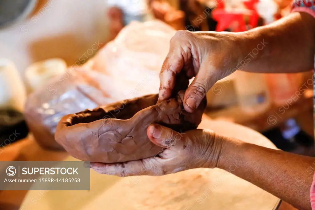 Hands of mixed race woman shaping clay in art studio