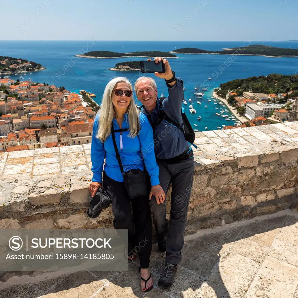 Caucasian couple posing for cell phone selfie with scenic view of ocean