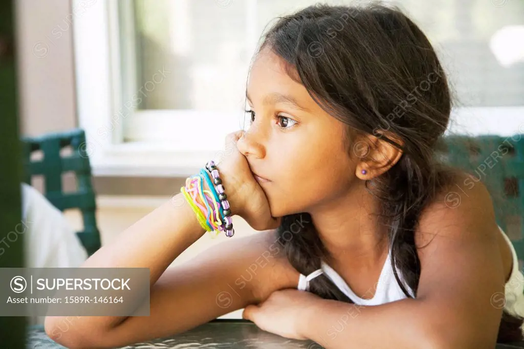 Pensive Hispanic girl with head in hands