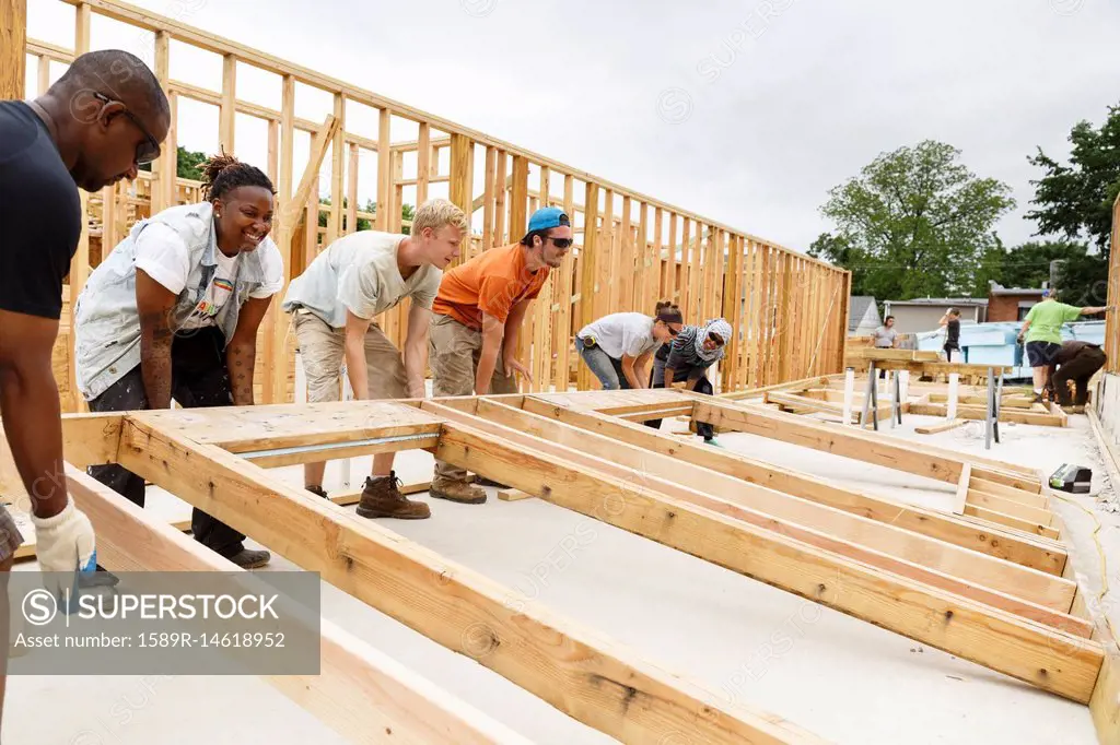 Volunteers lifting framed wall at construction site