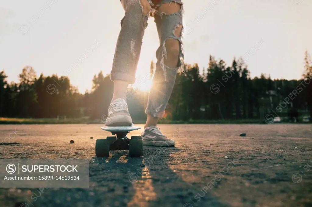 Legs of Caucasian teenage girl standing on skateboard